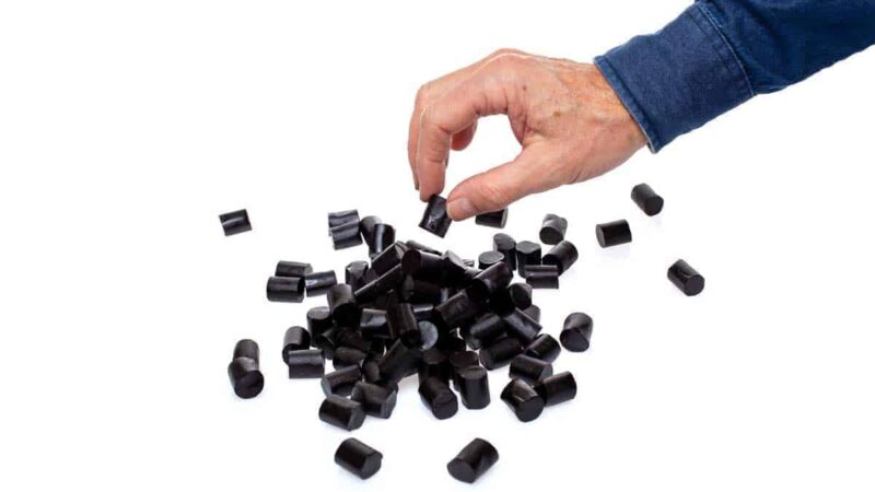 A hand picking from a pile of Dutch Strong Liquorice Pieces